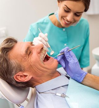 Dentist Checking Up Senior Man's Teeth — Grand Rapids, MI — Dentures In a Day