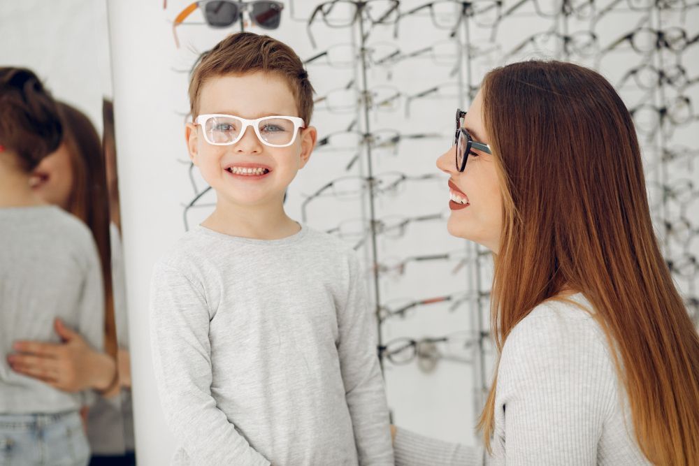 A woman and a boy are trying on glasses in an optical shop.