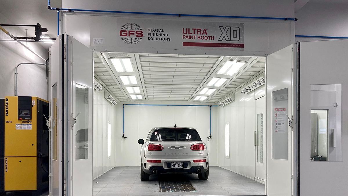 Une voiture est assise à l'intérieur d'une cabine de peinture.