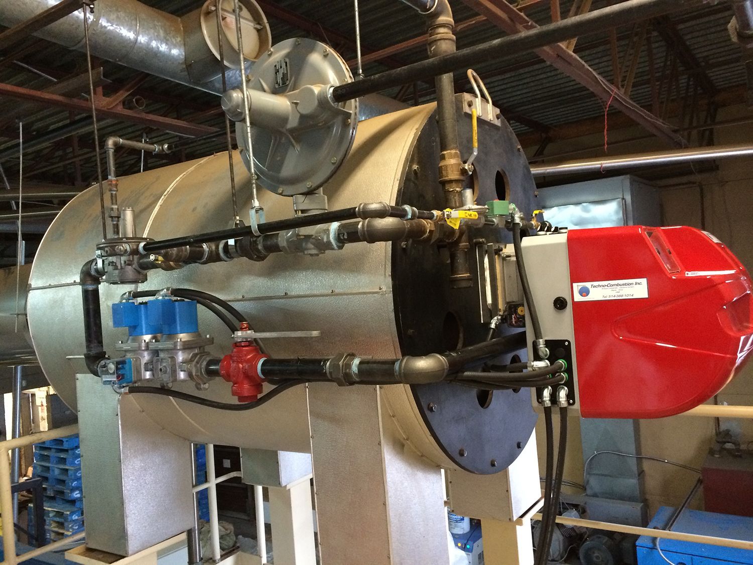 Une grande chaudière avec un brûleur rouge attaché dans une usine.