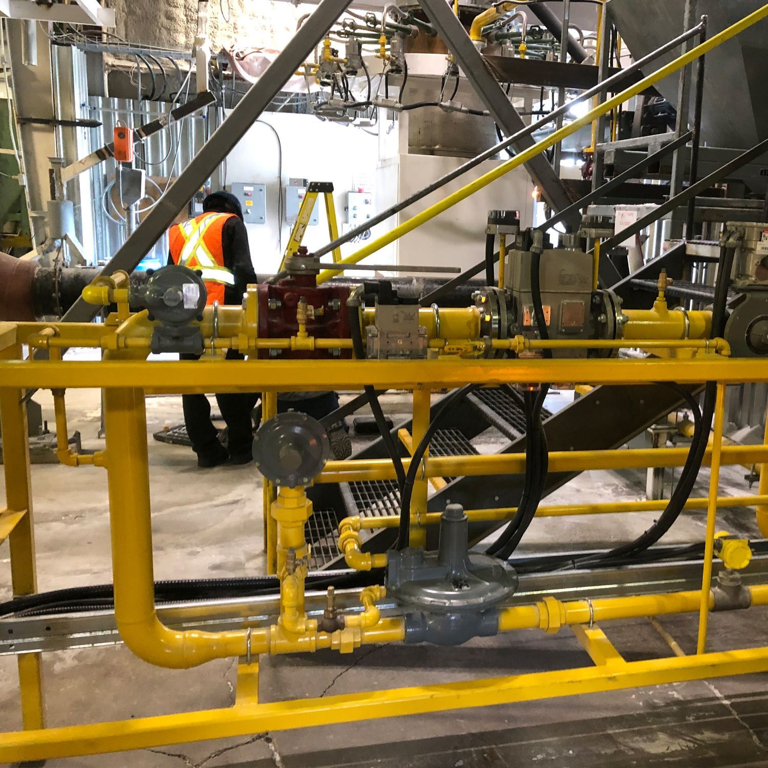 Un homme portant un gilet de sécurité travaille sur un système de tuyaux jaunes