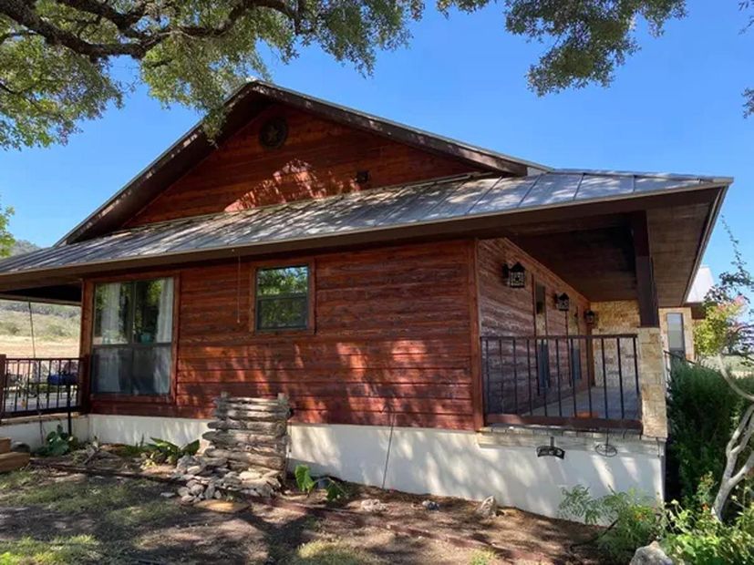 A small wooden house with a metal roof and a porch.