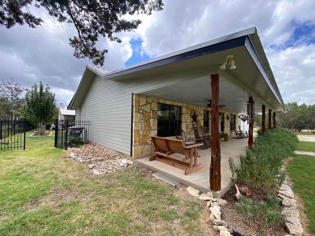 A house with a porch and a fence in the backyard.