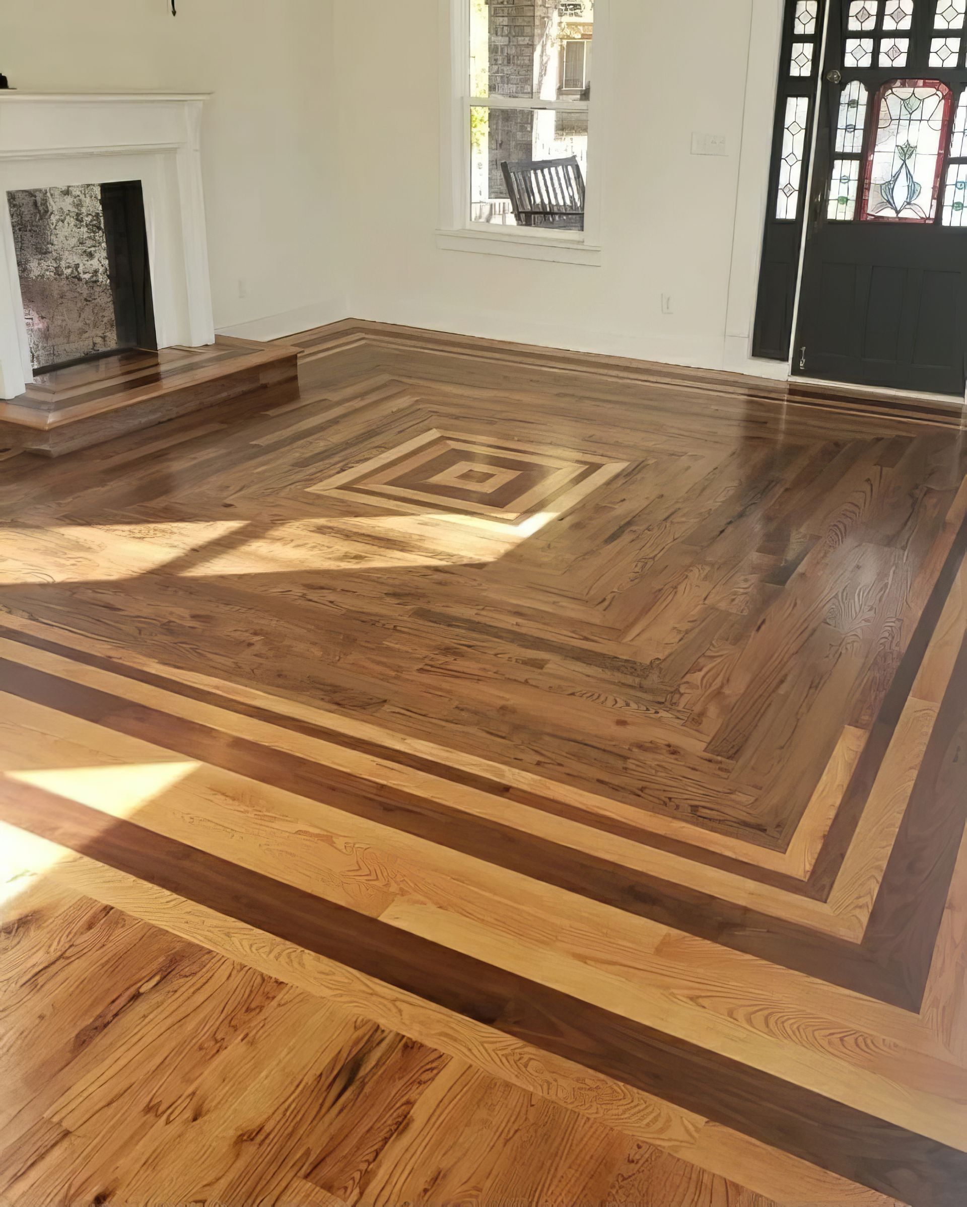 Hardwood floor with inlaid geometric design, in a bright room with a fireplace.