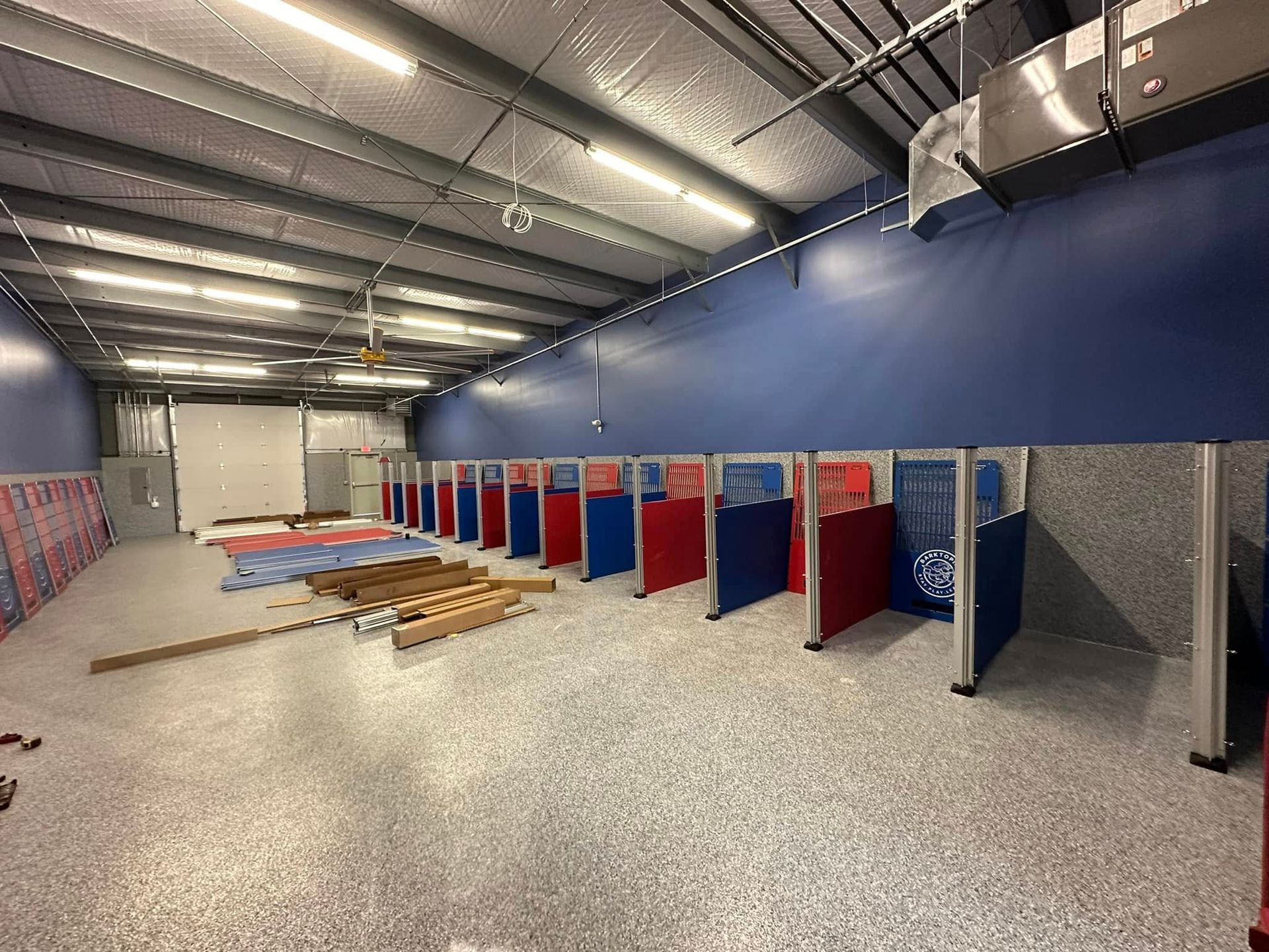 An empty shooting range with red and blue booths. Gray floor and blue and gray walls.