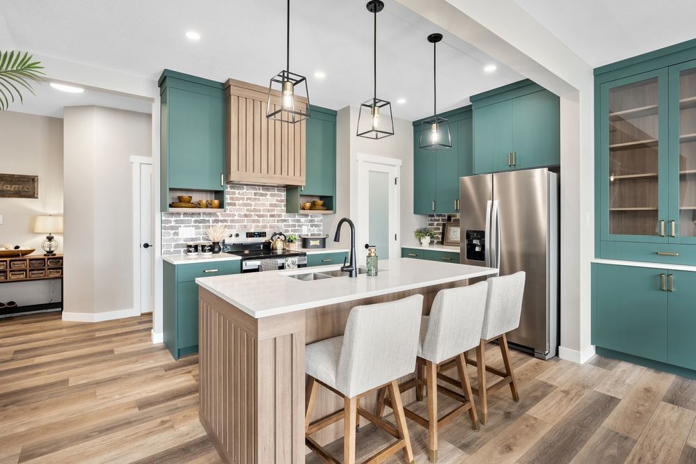 Kitchen with teal cabinets, light wood island with stools, and stainless steel appliances.