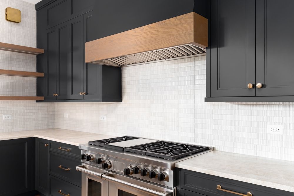 Dark gray kitchen with white countertops and backsplash, stainless steel range, and copper range hood.