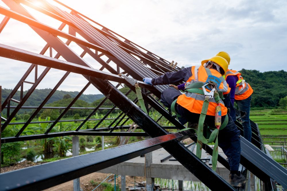 Workers in safety harnesses installing solar panels on a rooftop. Bright sunlight.