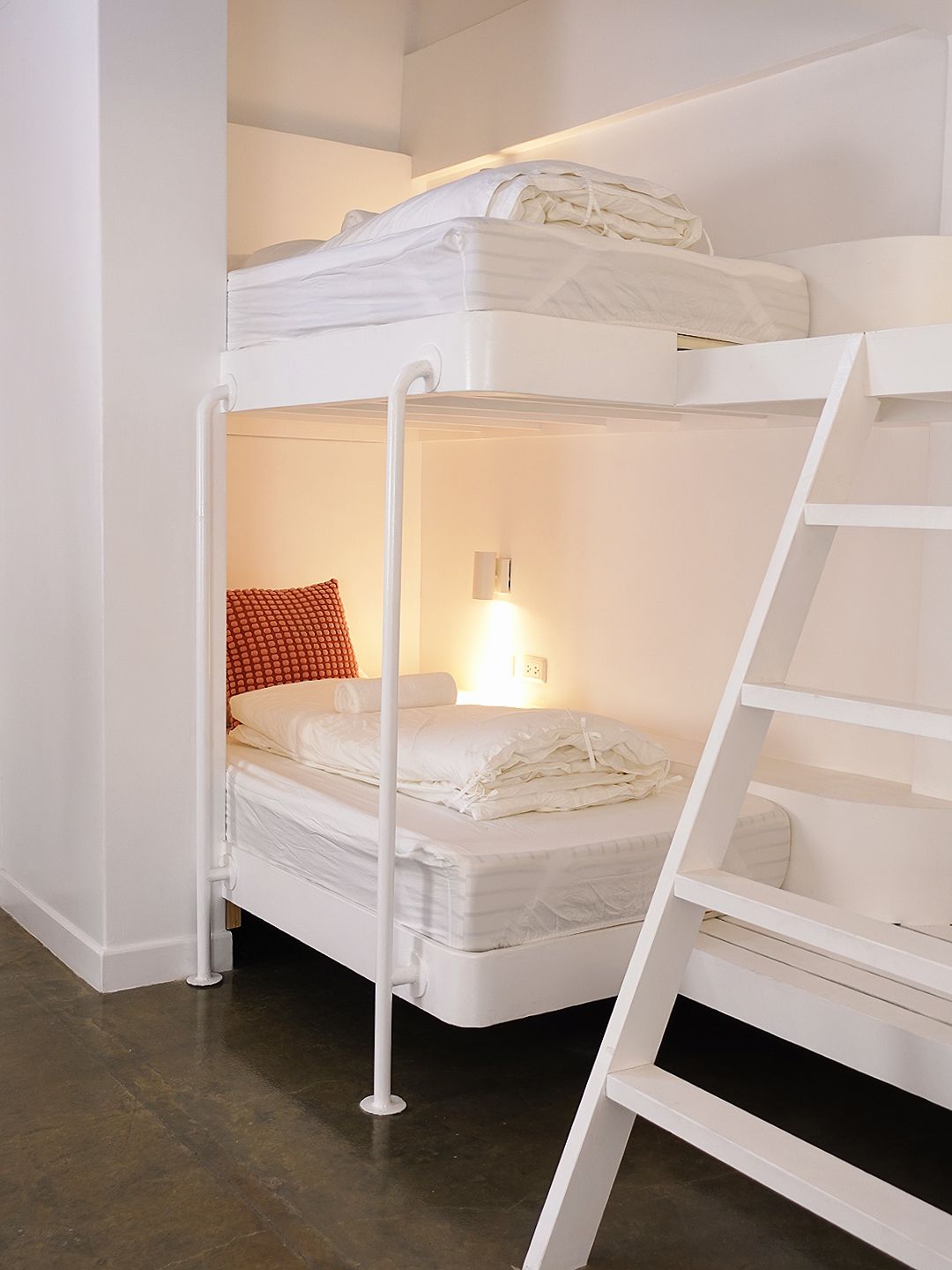 White bunk beds in a bright, modern room. A ladder provides access to the top bunk.