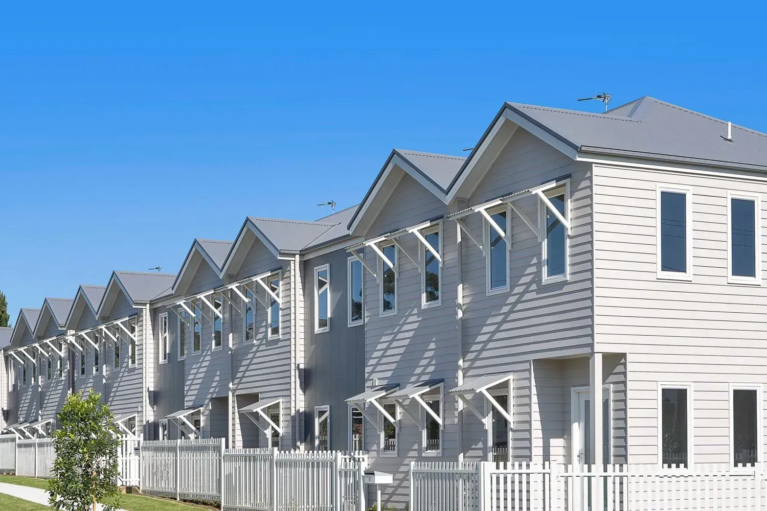 A Row of Houses With a White Fence — Sheps Roofing Service Pty Ltd In Shellharbour, NSW