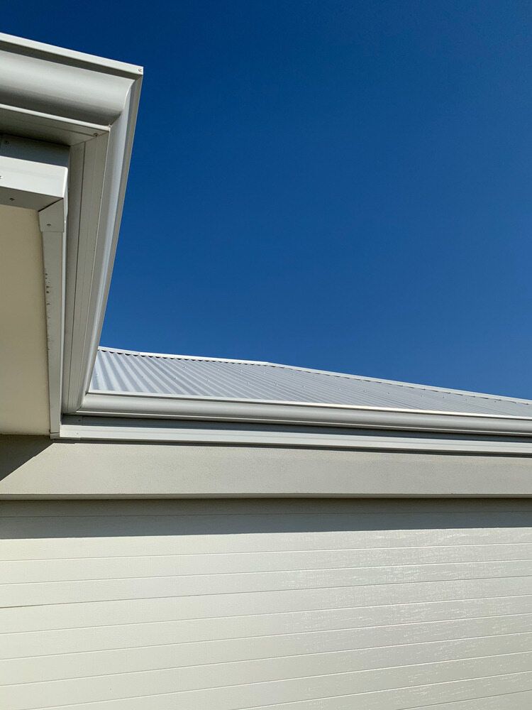 The Roof of a White House With a Blue Sky in the Background — Sheps Roofing Service Pty Ltd In Shellharbour, NSW