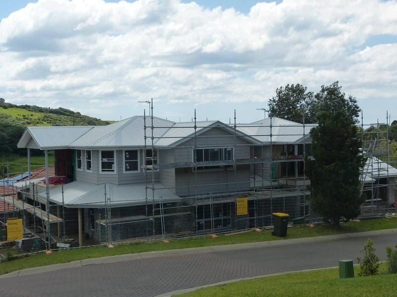 A Large House Under Construction With Scaffolding Around It — Sheps Roofing Service Pty Ltd In Kiama, NSW