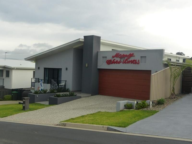 A House With a Red Garage Door and a Sign That Says Happy Holidays — Sheps Roofing Service Pty Ltd In Albion Park, NSW