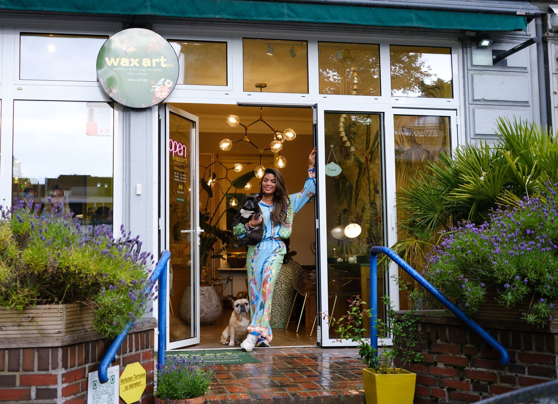 Eingangs-Bereich von Wellness-Brazilian Waxing-Studio, und die Besitzerin lehnt entspannt am Türrahmen.