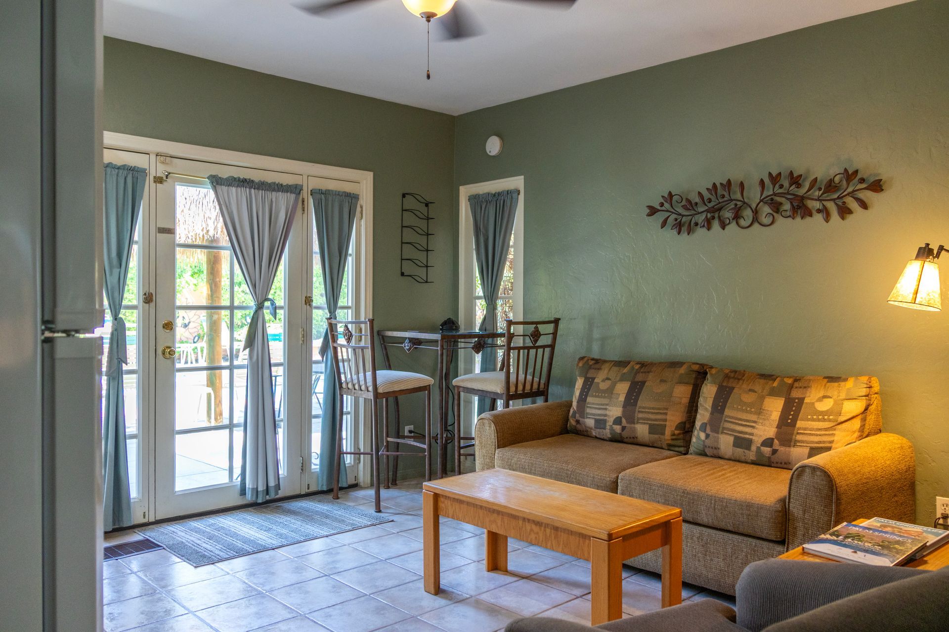 Cozy living room with olive green walls, a brown couch, and French doors leading to a patio.