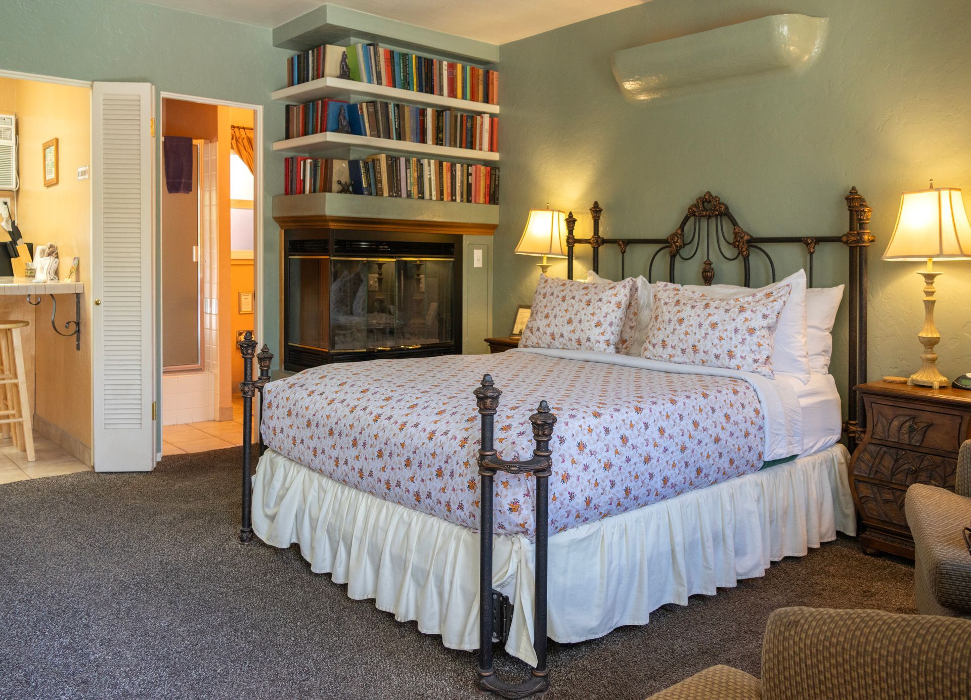 Bedroom with bed, fireplace, bookshelf, and access to another room.