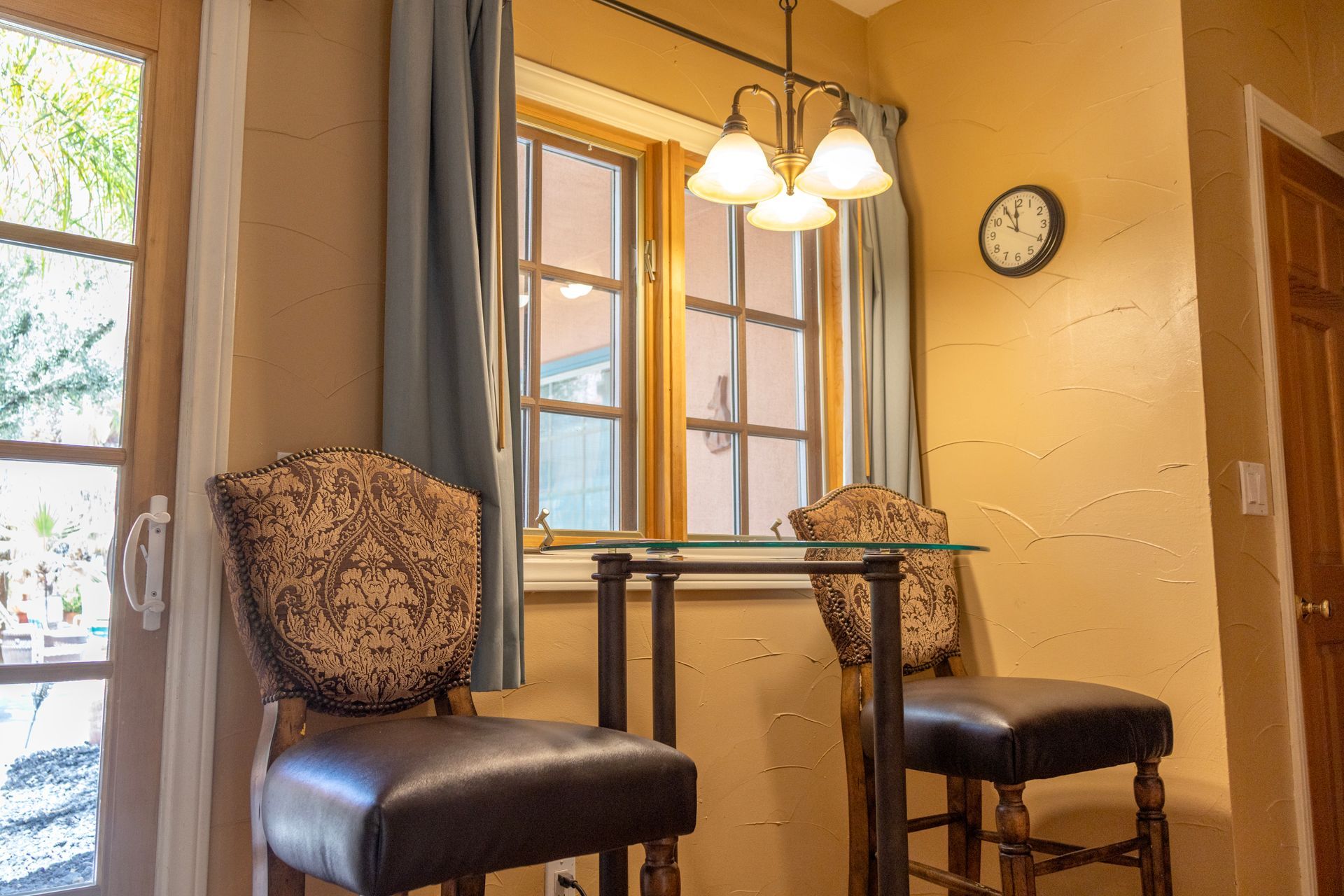 Small dining area with table, two chairs, window, and hanging light fixture.