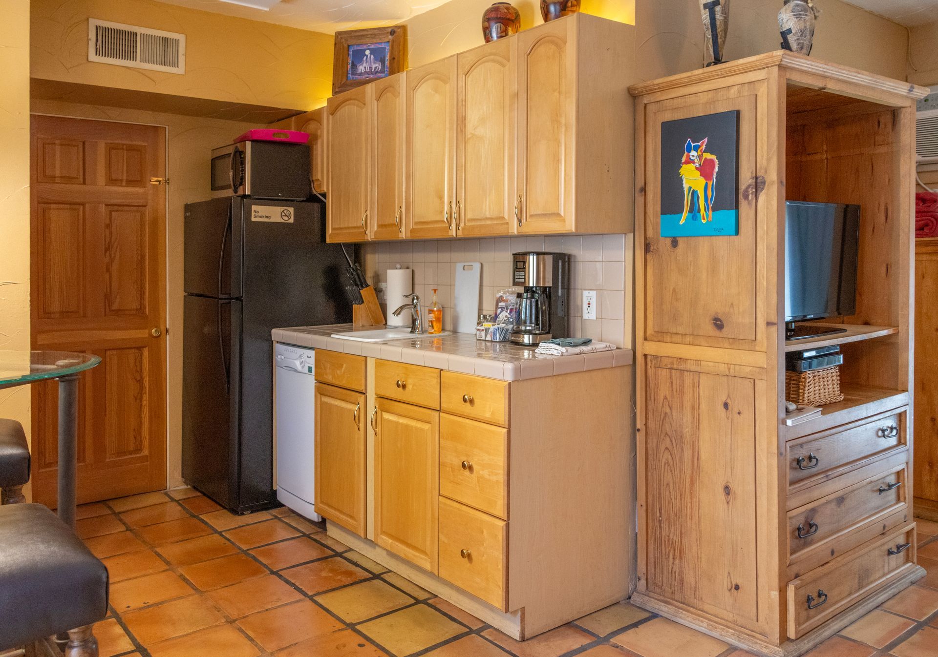 Small kitchen with wood cabinets, appliances, and tiled floor.