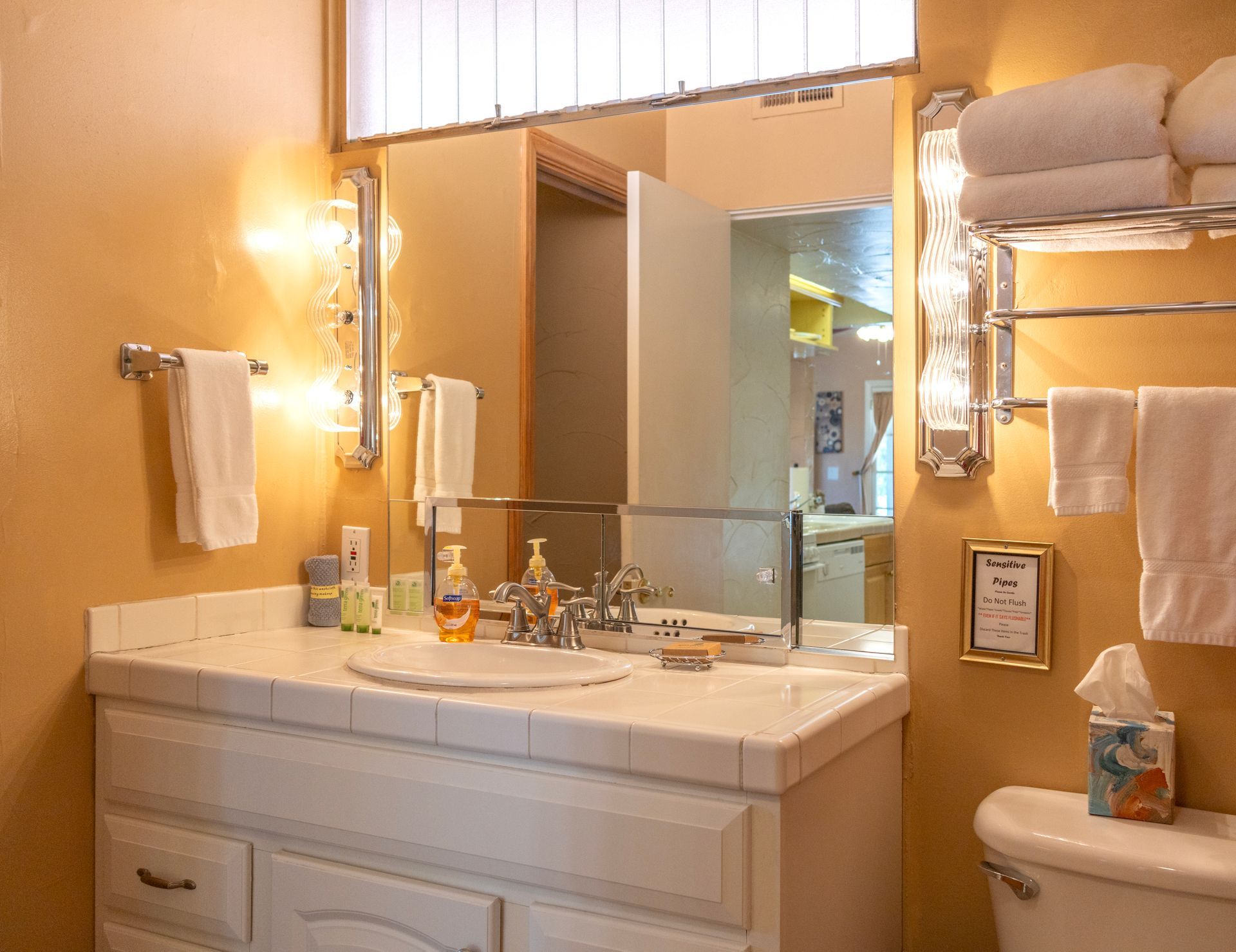 Bathroom with a white vanity, towels, and mirror. Cream and yellow walls.