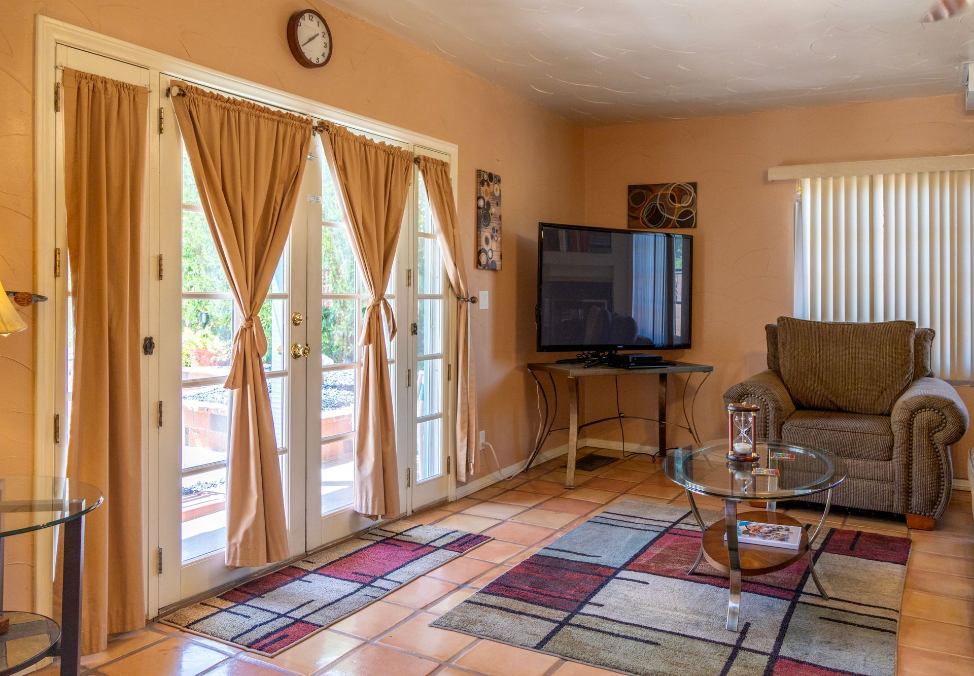 Living room with French doors, a TV, armchair, rug, and tan walls.