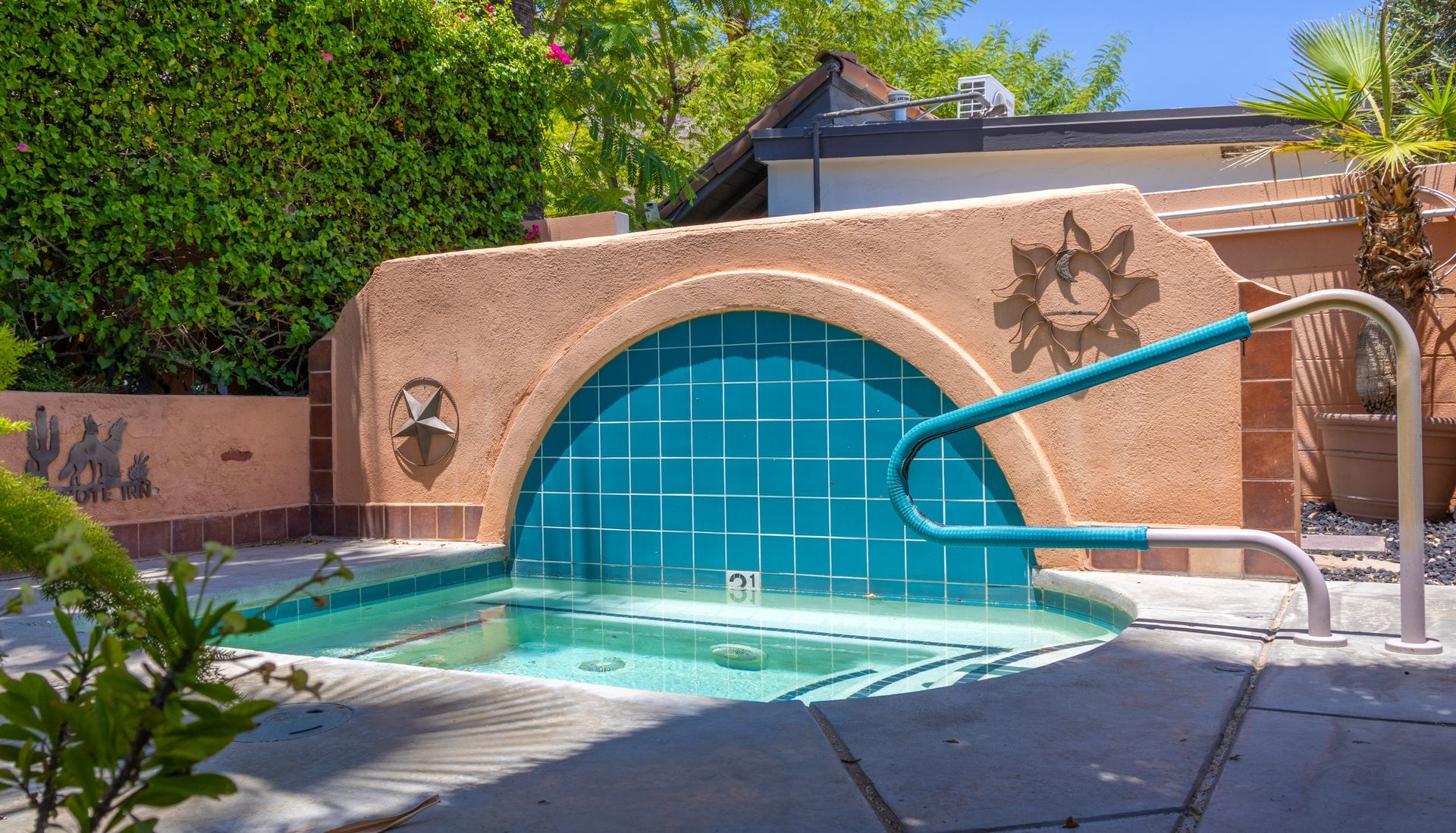 Small turquoise tiled pool with a curved wall and handrails.