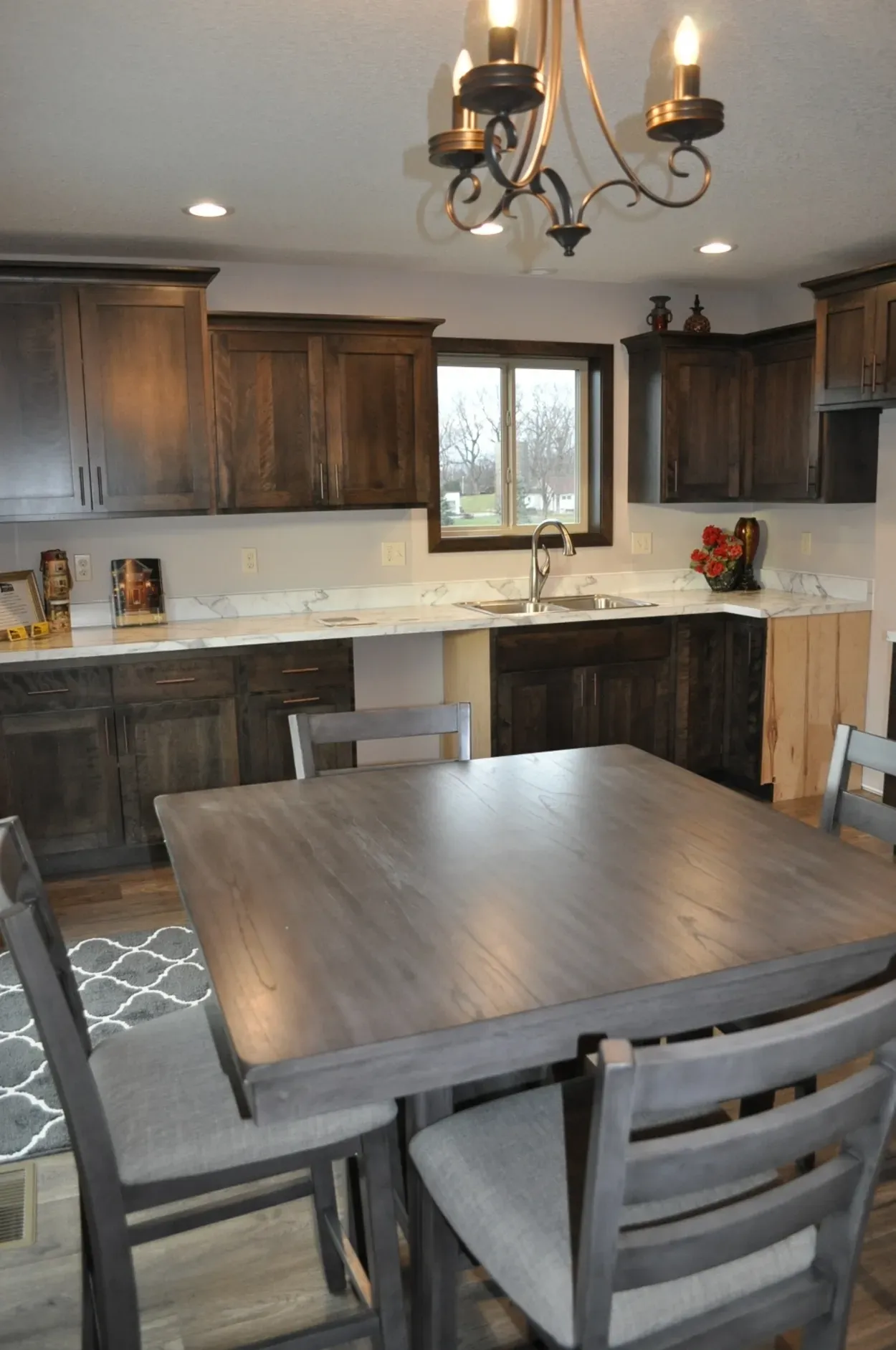 Kitchen with dark wooden cabinets, white countertops, and a gray square table with chairs.