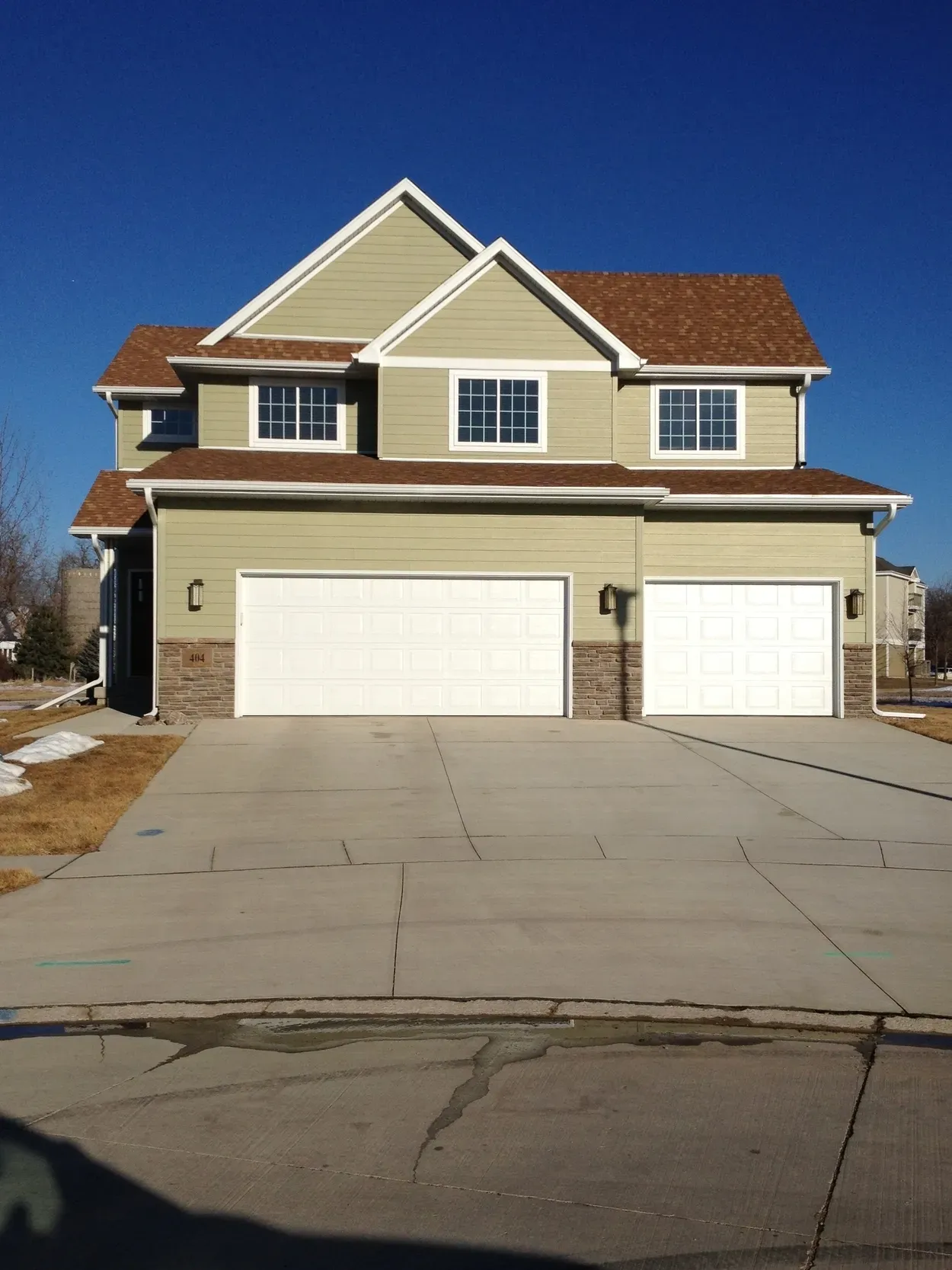 Two-story house with green siding, brown roof, and two-car garage. 