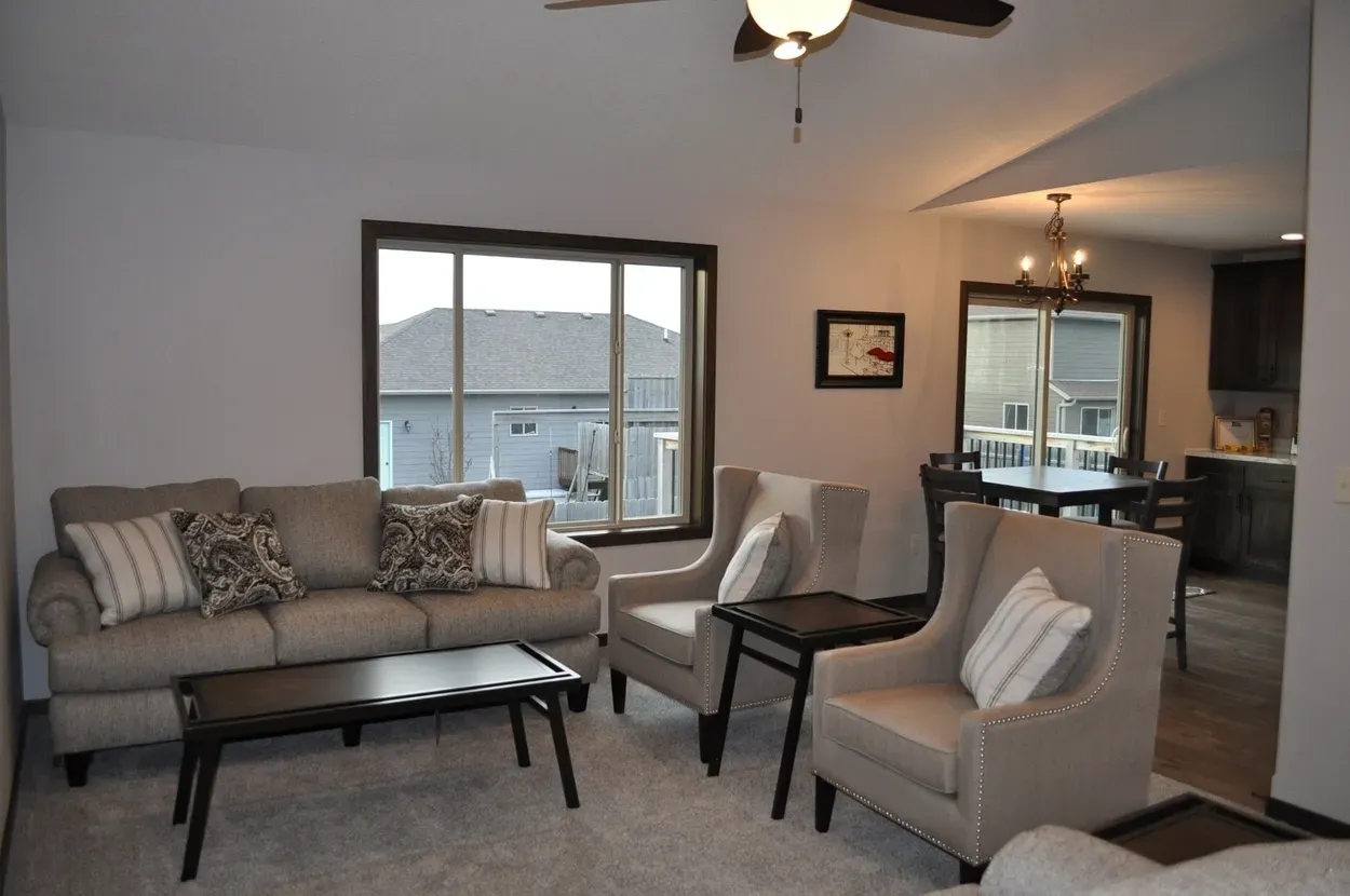 Living room with neutral furniture, large window, and open dining area.