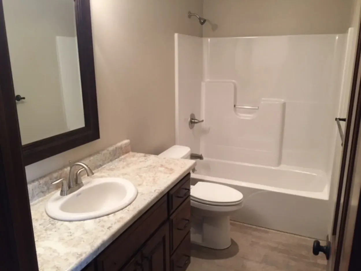 Bathroom with white fixtures, dark wood vanity, light-colored floor, and beige walls.
