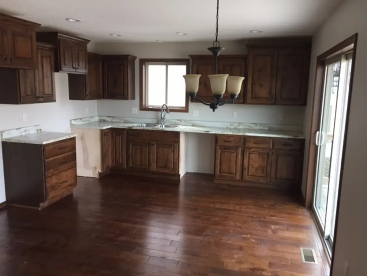 Kitchen with brown cabinets, light countertops, and dark hardwood floor.