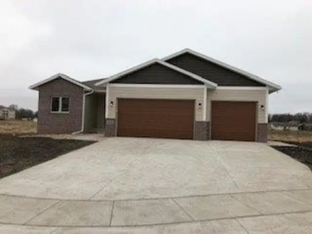 Tan house with brown garage doors and a concrete driveway.