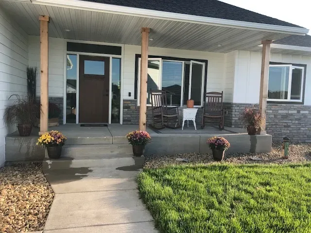 Front porch of a modern house, with rocking chairs and potted plants.