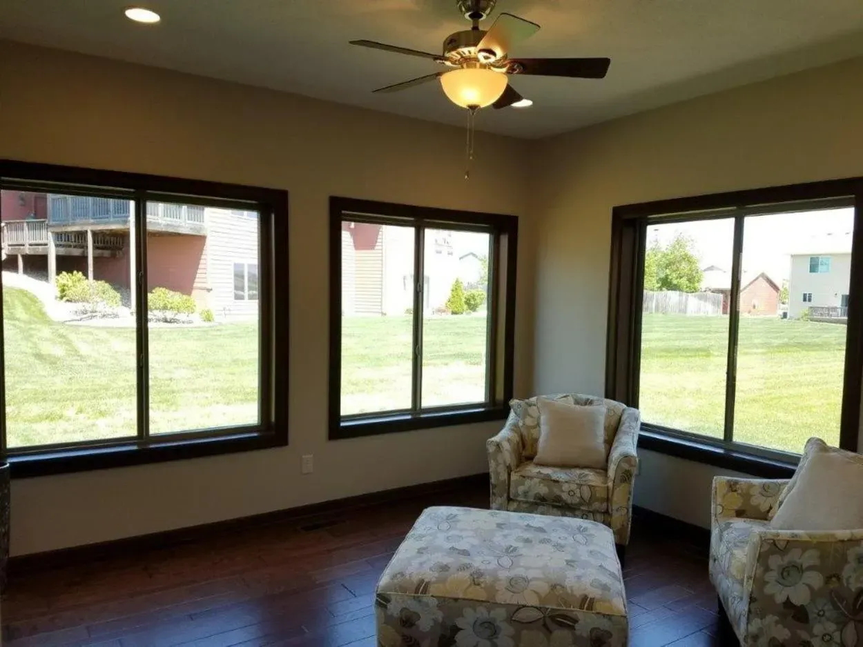 Sunroom with three large windows overlooking a green lawn.