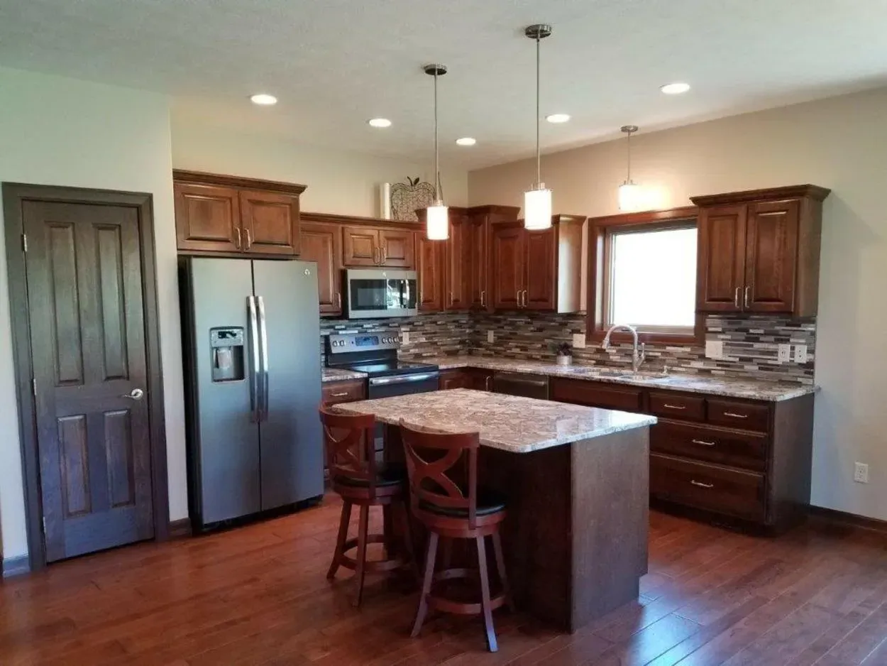 Kitchen with wood cabinets, stainless steel appliances, and island with bar stools.