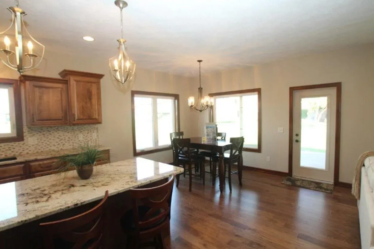 Kitchen with granite island, wooden cabinets and flooring.