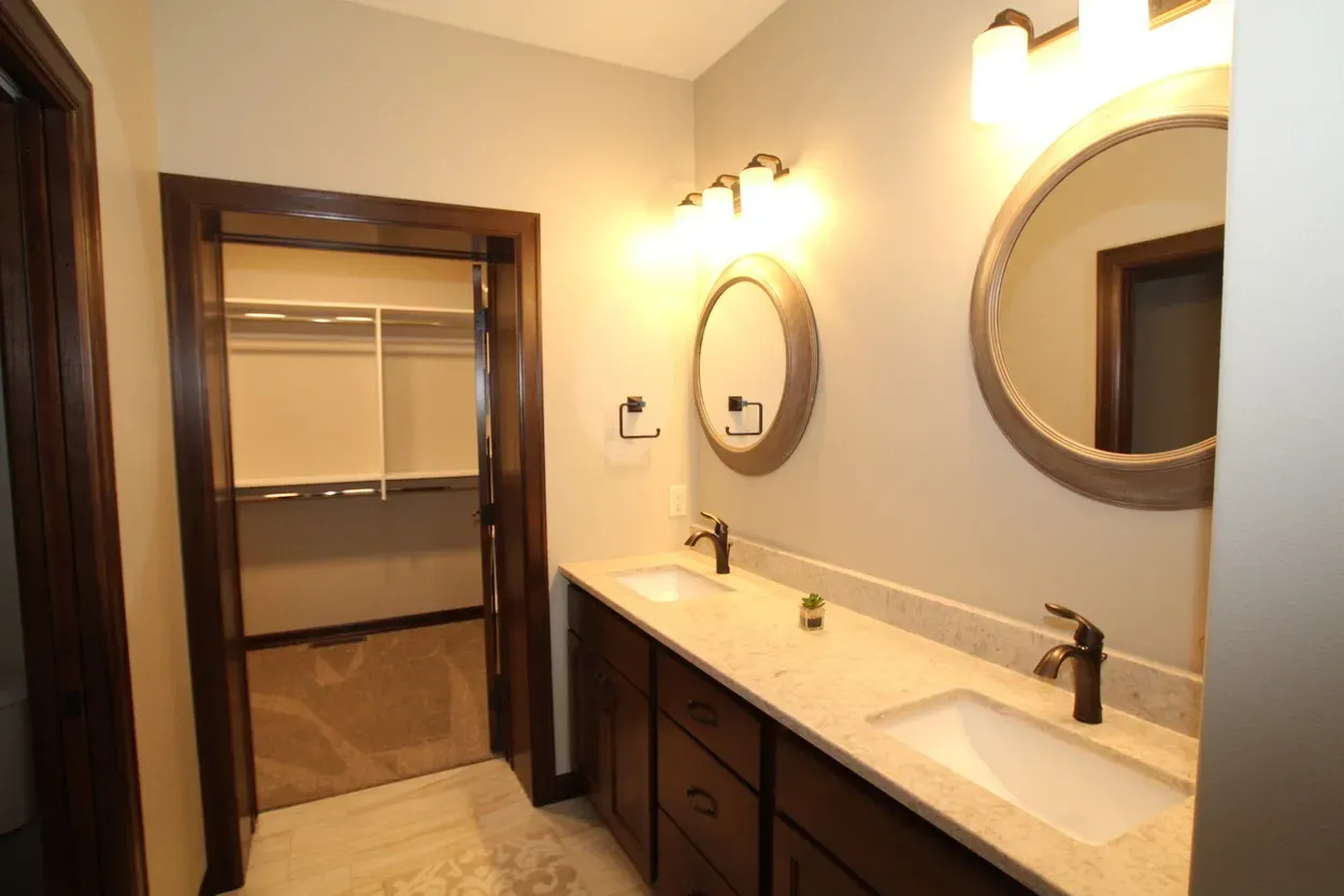 Bathroom with double sink vanity, circular mirrors, and a closet.