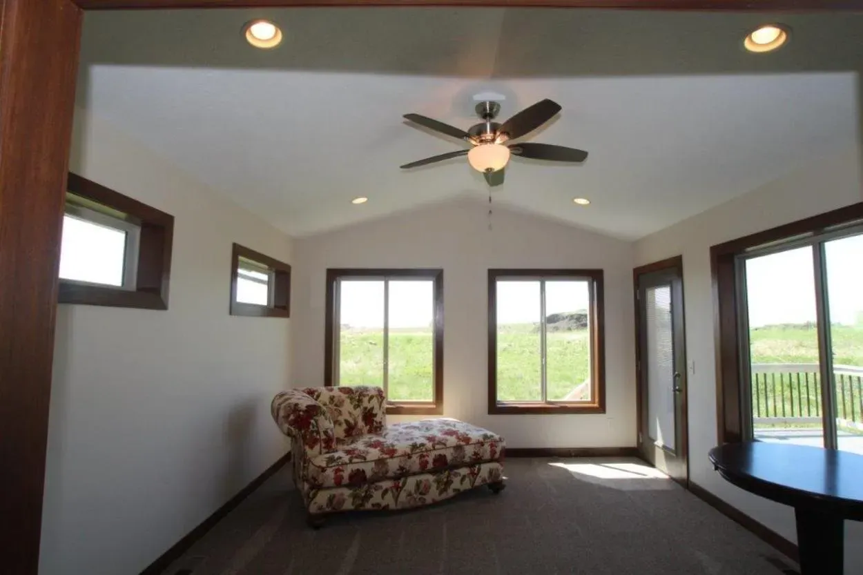 Sunroom with brown trim, beige walls, and floral chaise lounge. 