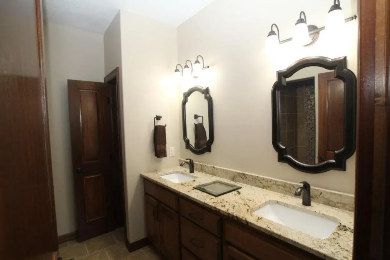 Bathroom with double sinks, mirrors, and dark wooden cabinets.