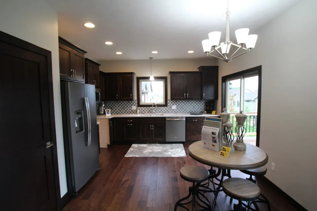 Kitchen with dark cabinets, stainless steel appliances, and a small dining table.