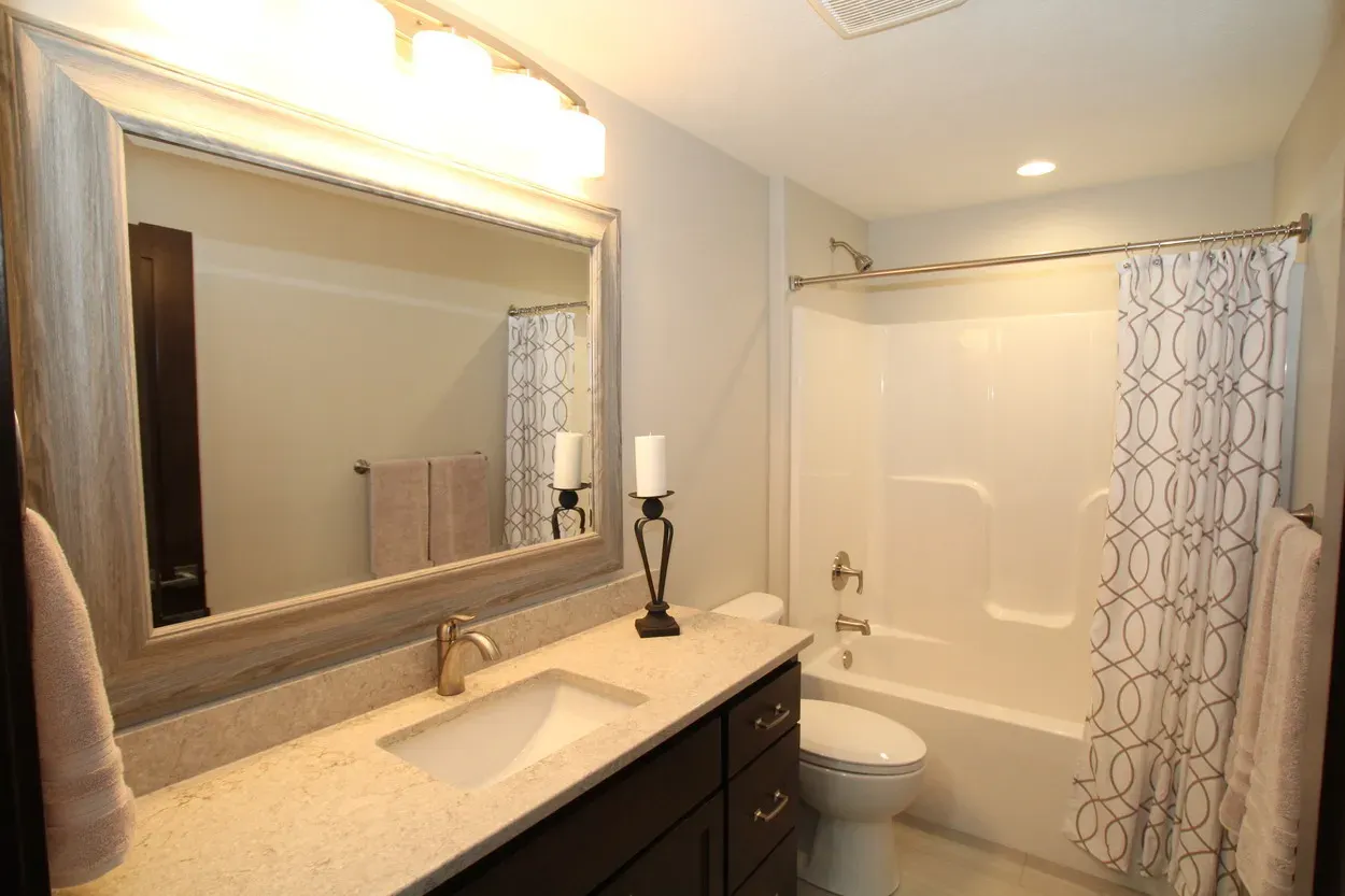 Bathroom with white fixtures, dark cabinets, and patterned shower curtain.