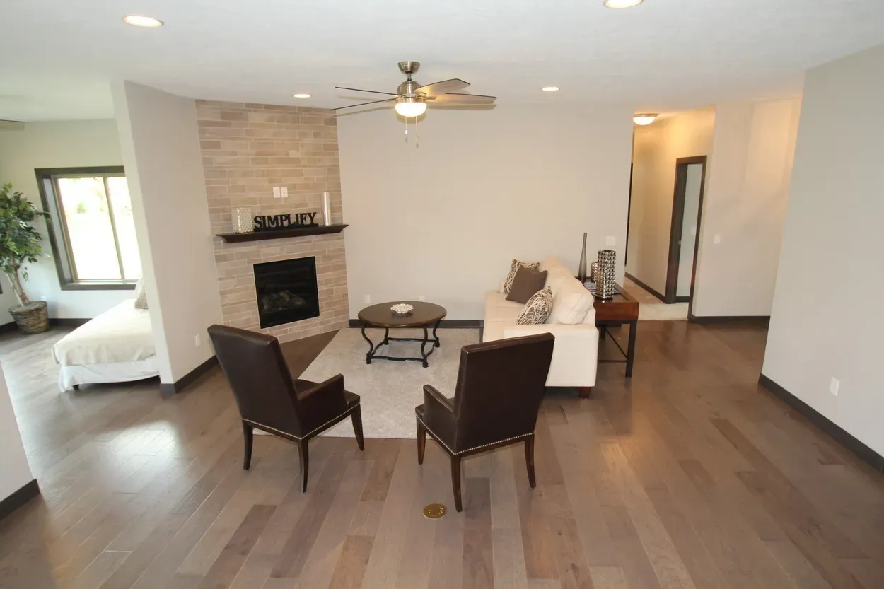 Living room with fireplace, two armchairs, white couch, and dark hardwood floors.