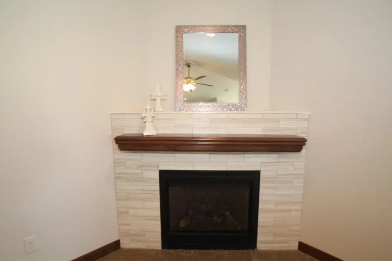 Fireplace with light-colored tile surround, dark mantel, black firebox, and a mirror above.