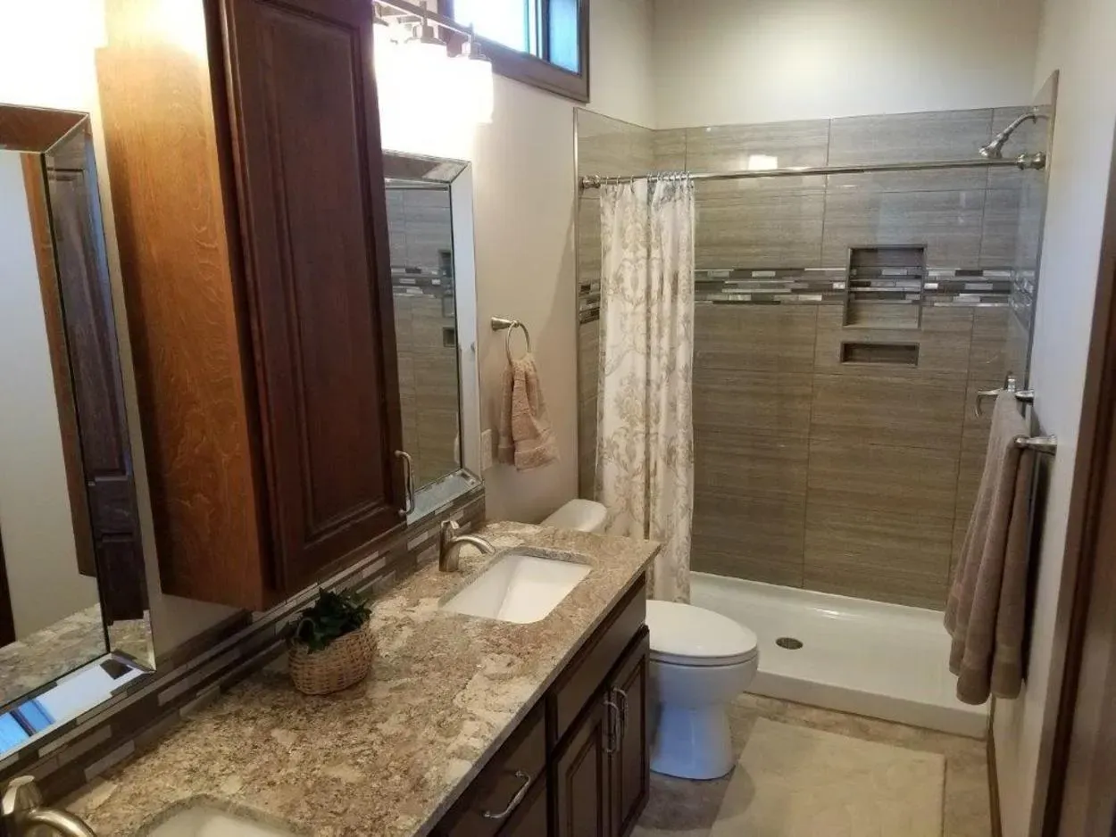 Bathroom with vanity, toilet, and tiled shower.