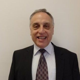 Smiling man in a suit and tie against a plain background.