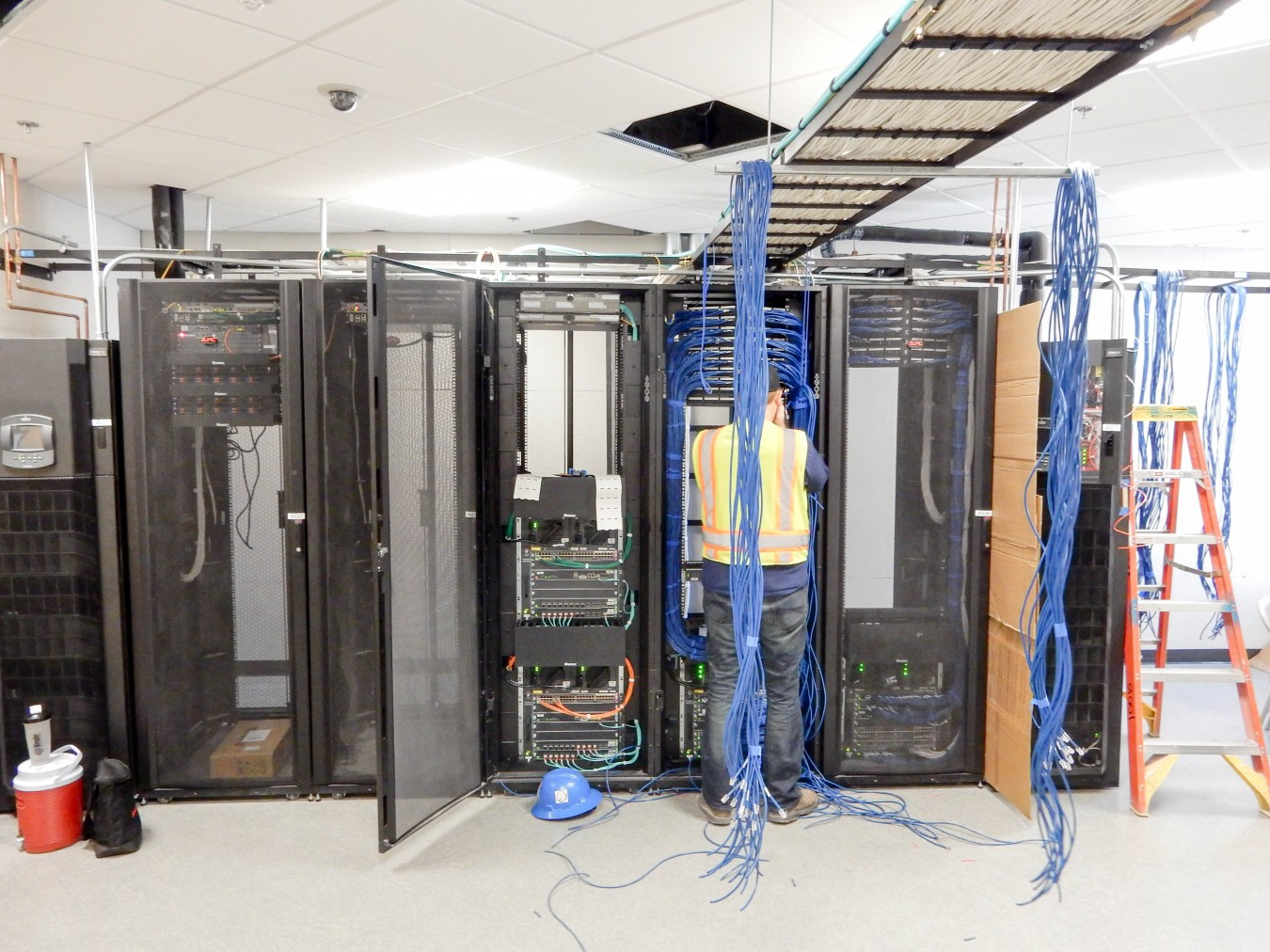 Two technicians work on server cables in a data center, focused on the equipment.