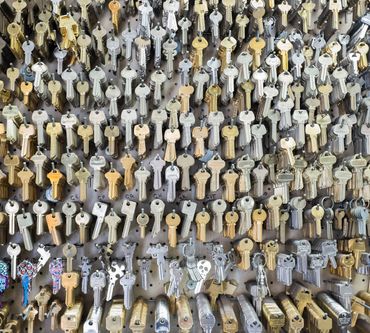 A wall covered with many keys of various shapes and colors, presumably at a locksmith shop.