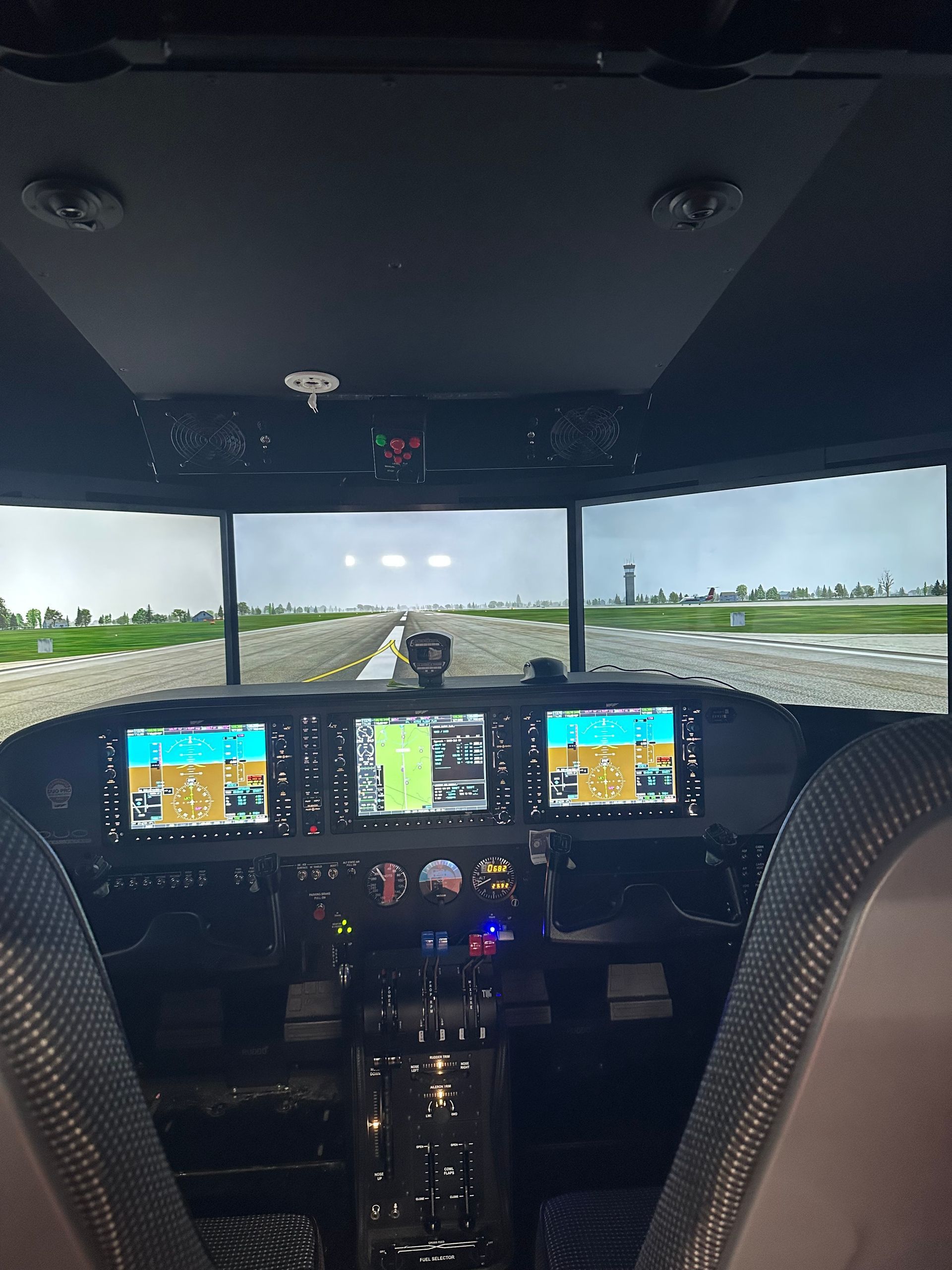 Cockpit view of a small plane taxiing on a runway, with illuminated flight displays and green fields ahead.