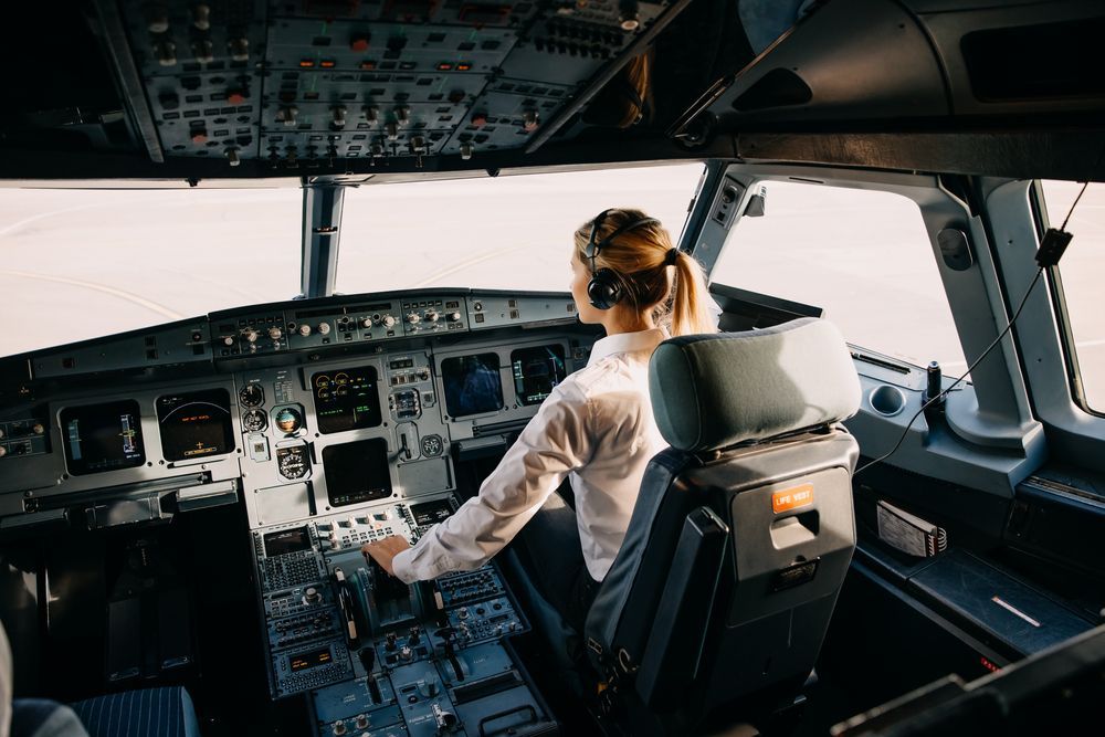 A woman is sitting in the cockpit of an airplane.