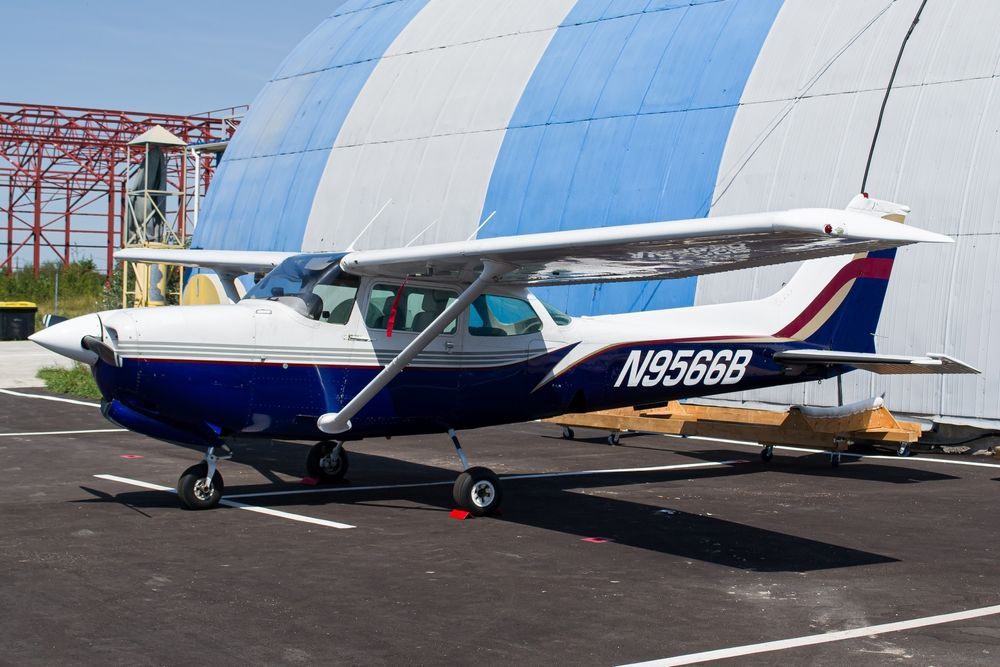 A Cessna 172RG next to a hangar.