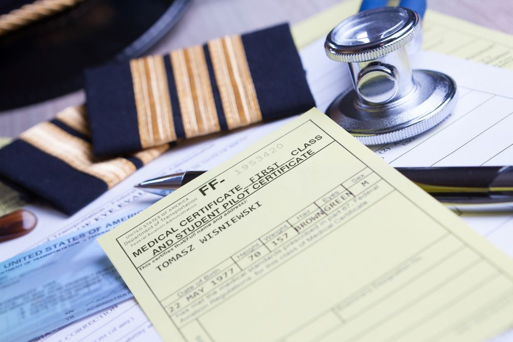 A closeup of an airplane pilot's first class medical certificate and student pilot certificate.